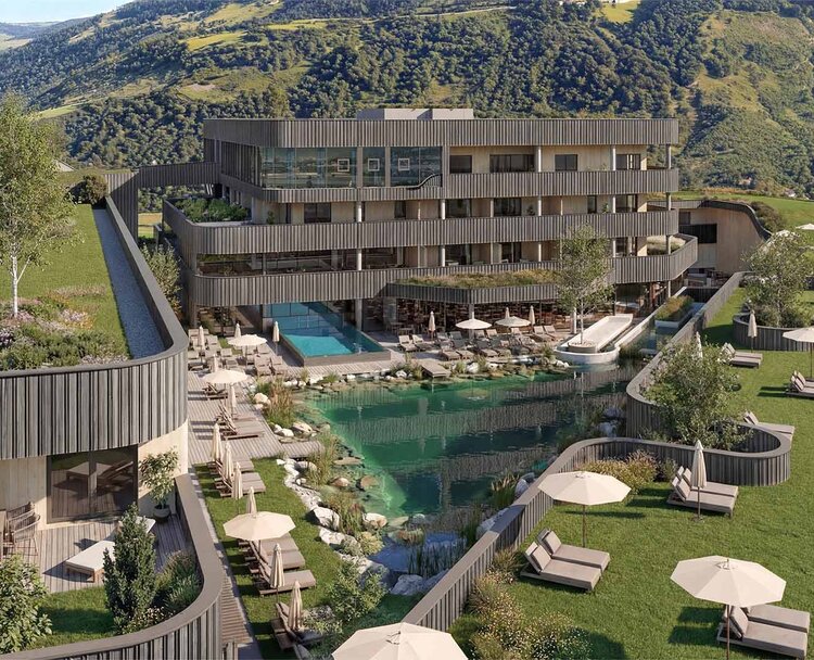 TheGreen-Visualisierung-Aussenaufnahme-1 Mehrstöckiges modernes Hotelgebäude mit Holzfassade vor bewaldeten Berg und einem natürlichen Schwimmteich mit Liegestühlen und Sonnenschirmen auf einer Wiese