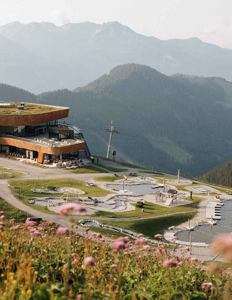 Bergstation einer Gondelbahn, umgeben von einer sommerlichen Berglandschaft