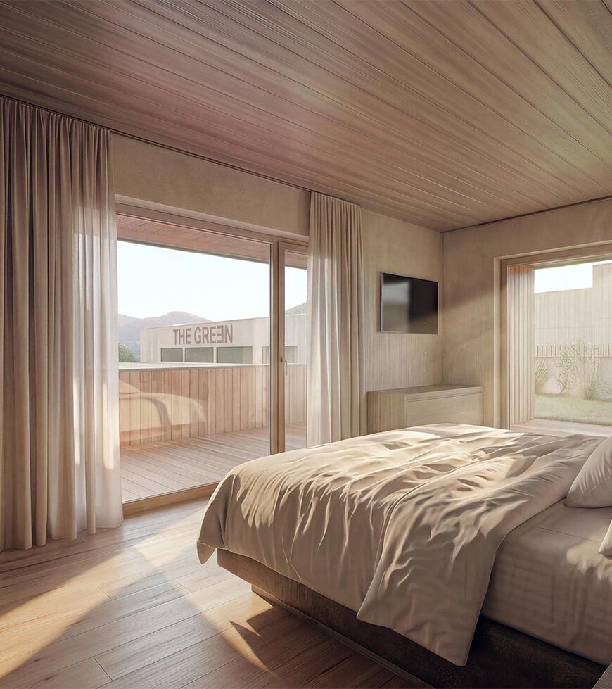 thegreen-zimmer-haupthaus-1 Schlafzimmer mit großem Bett, Holzwänden und -boden, Zugang zu Balkon mit Sitzmöbeln
