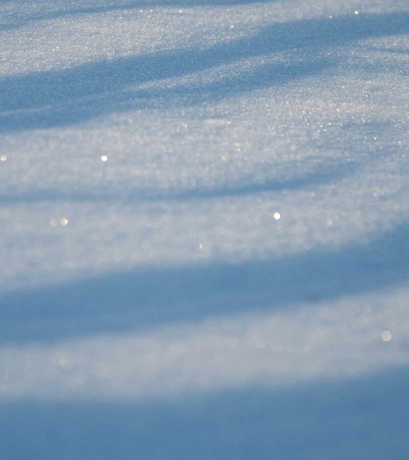 Nahaufnahme von glitzerndem Schnee mit Schattenstreifen
