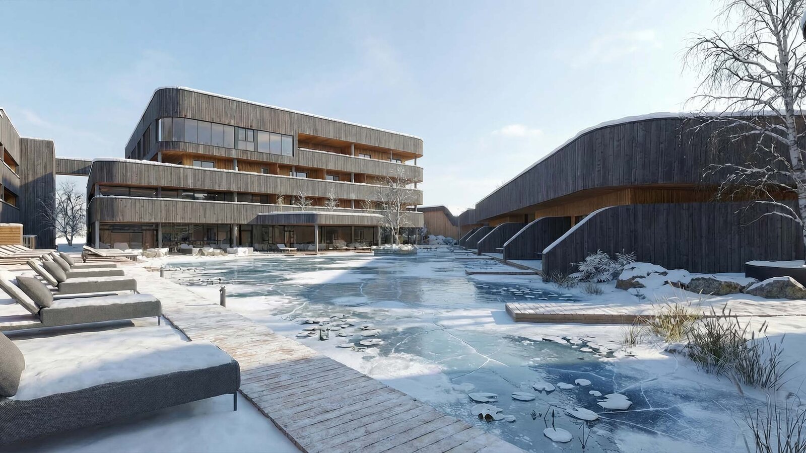 Moderner Gebäudekomplex mit Holzfassaden und gefrorenem Teich im Vordergrund bei winterlicher Landschaft